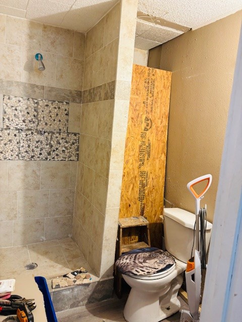 bathroom featuring a tile shower and toilet