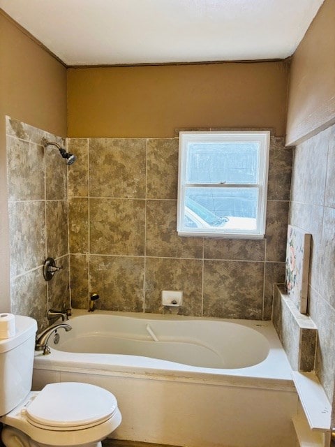 bathroom with tiled shower / bath combo and toilet