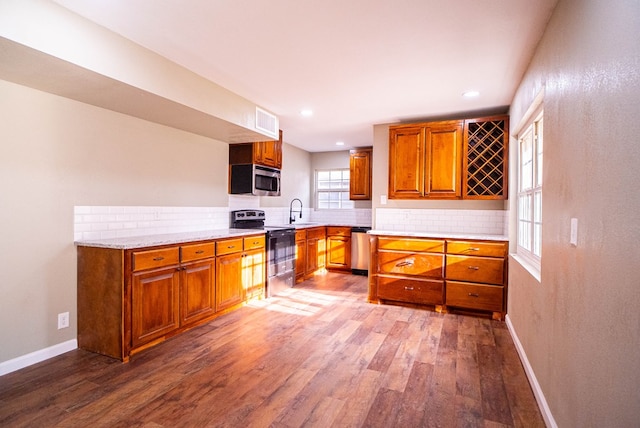 kitchen with stainless steel appliances, sink, wood-type flooring, and backsplash