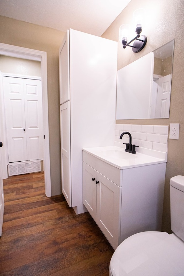 bathroom with wood-type flooring, vanity, backsplash, and toilet