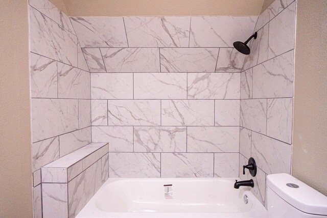 bathroom with toilet and tiled shower / bath