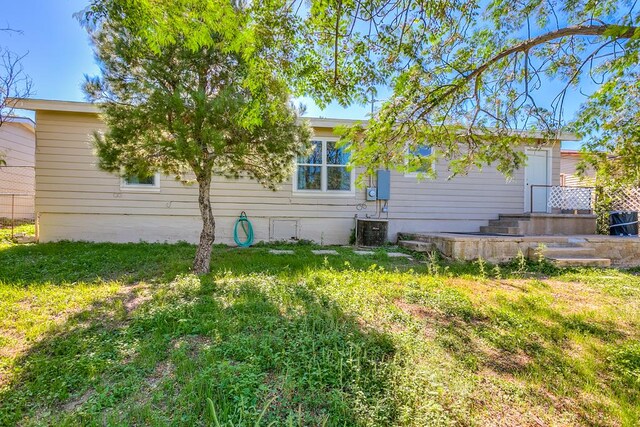 view of side of property with central AC unit and a lawn