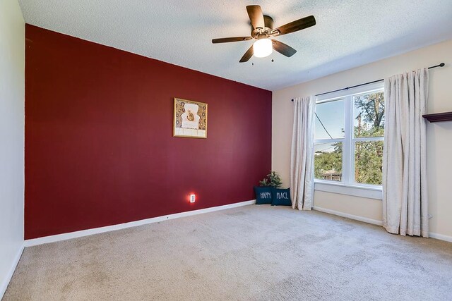 carpeted empty room with ceiling fan and a textured ceiling