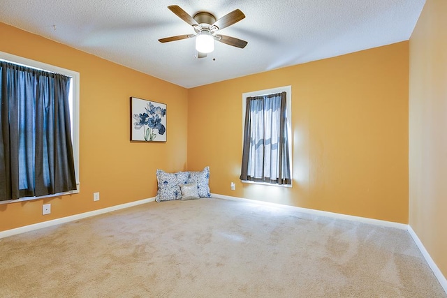 empty room featuring ceiling fan, a textured ceiling, and carpet