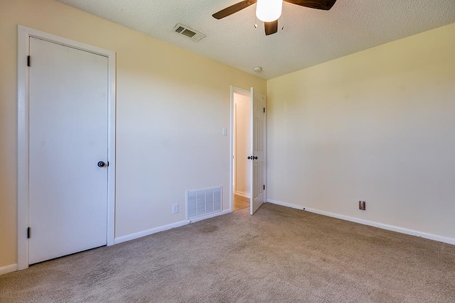 empty room featuring ceiling fan, light colored carpet, and a textured ceiling