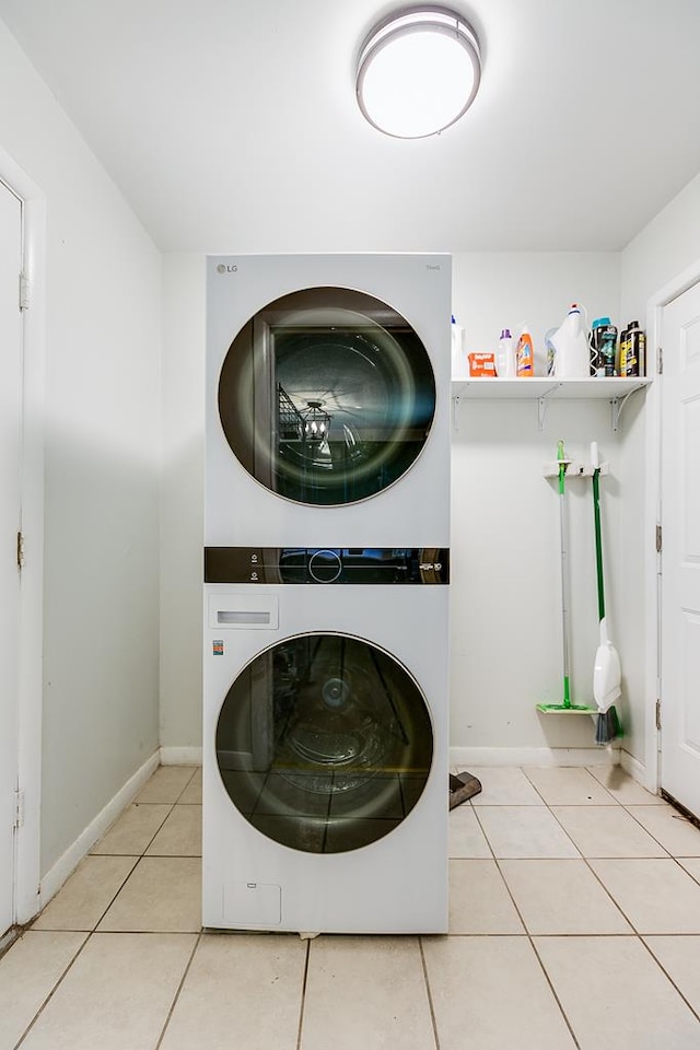 clothes washing area with light tile patterned floors and stacked washer and clothes dryer