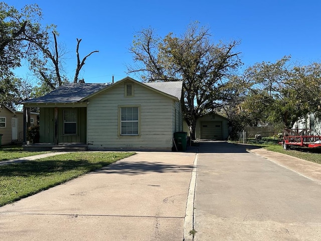 view of front of house featuring driveway, a garage, a front lawn, and an outbuilding