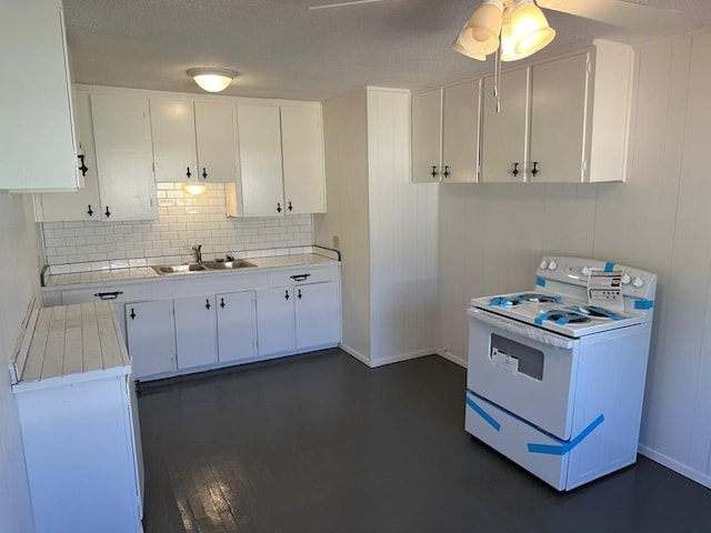 kitchen with tasteful backsplash, white range with electric cooktop, tile countertops, white cabinetry, and a sink