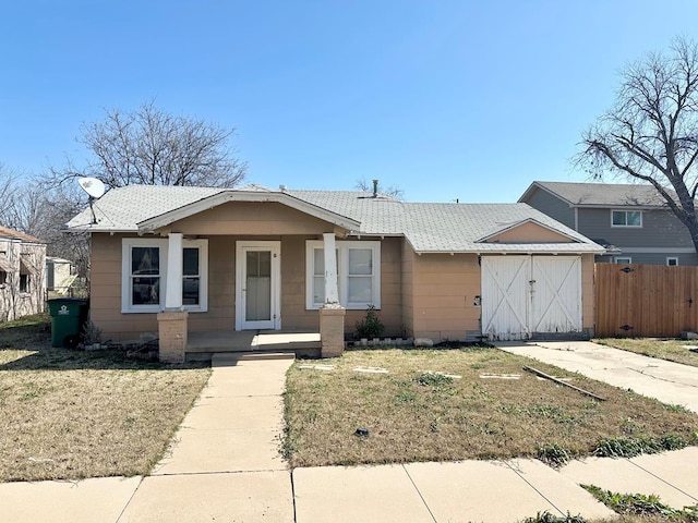 bungalow-style home with a garage, a porch, a front yard, and fence