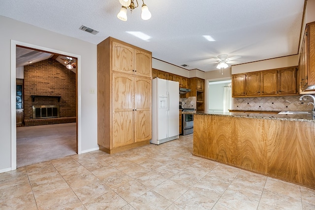 kitchen featuring tasteful backsplash, sink, white fridge with ice dispenser, a brick fireplace, and stainless steel electric range