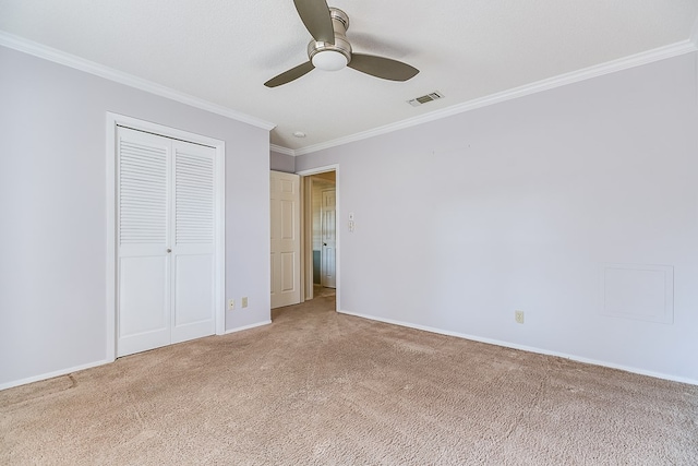 unfurnished bedroom featuring crown molding, carpet flooring, ceiling fan, and a closet