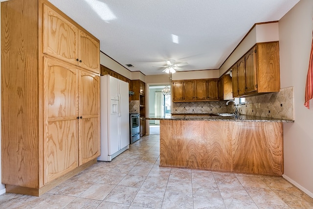 kitchen with tasteful backsplash, sink, white refrigerator with ice dispenser, ceiling fan, and kitchen peninsula