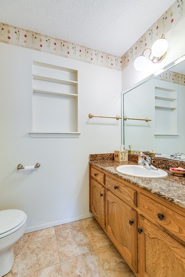 bathroom with vanity, toilet, and a textured ceiling