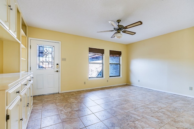 entrance foyer featuring a textured ceiling, ceiling fan, and light tile patterned flooring