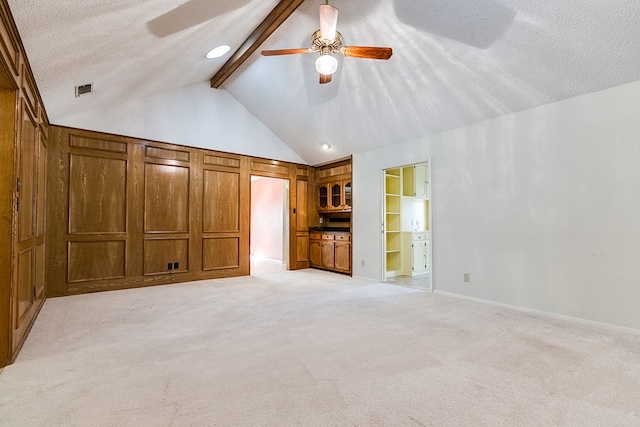 unfurnished living room featuring vaulted ceiling with beams, light carpet, a textured ceiling, built in features, and ceiling fan