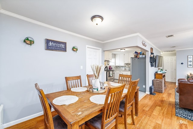 dining space featuring crown molding and light hardwood / wood-style floors