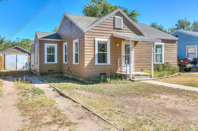 bungalow-style home featuring a front lawn and a storage unit