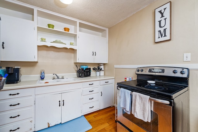 kitchen with sink, stainless steel electric range oven, white cabinets, a textured ceiling, and light wood-type flooring