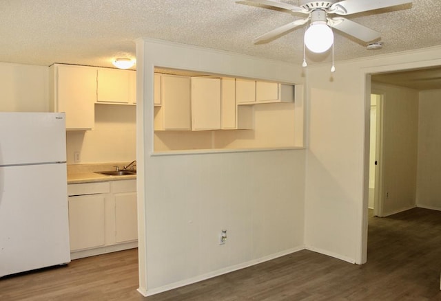 kitchen with white refrigerator, wood-type flooring, crown molding, and a textured ceiling