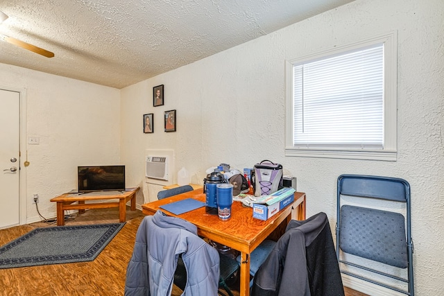 dining space featuring hardwood / wood-style floors, a wall mounted air conditioner, and a textured ceiling