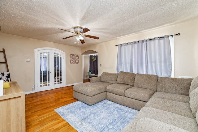 living room with hardwood / wood-style flooring, ceiling fan, french doors, and a textured ceiling