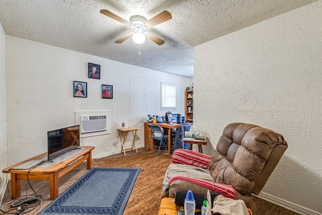 living area with ceiling fan, hardwood / wood-style flooring, a textured ceiling, and a wall mounted AC