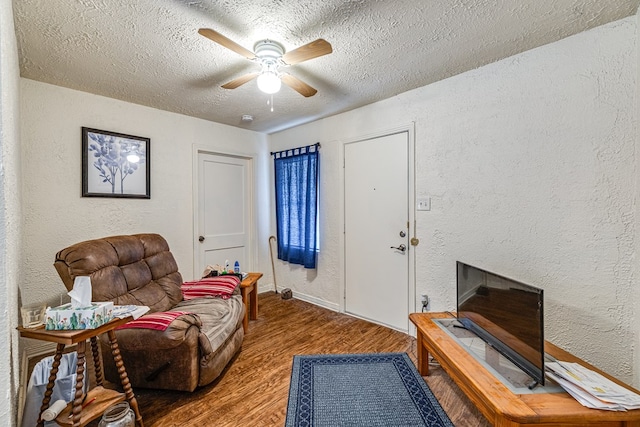 living area with wood-type flooring, a textured ceiling, and ceiling fan