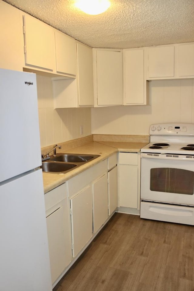 kitchen with sink, white appliances, white cabinetry, dark hardwood / wood-style floors, and a textured ceiling