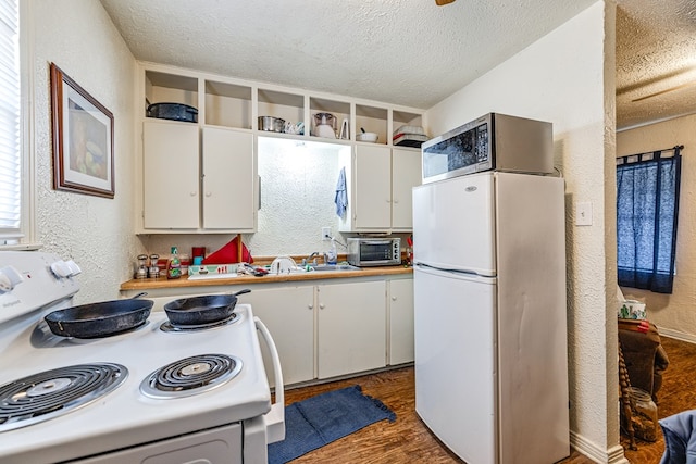 kitchen with white cabinetry, dark hardwood / wood-style floors, a textured ceiling, and white appliances