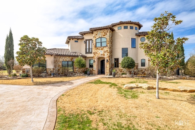 mediterranean / spanish home featuring stone siding, a tile roof, and stucco siding