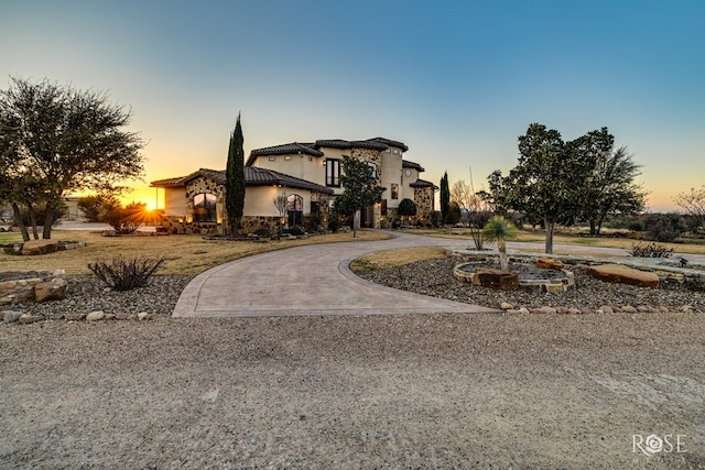 view of front of home featuring curved driveway and stucco siding