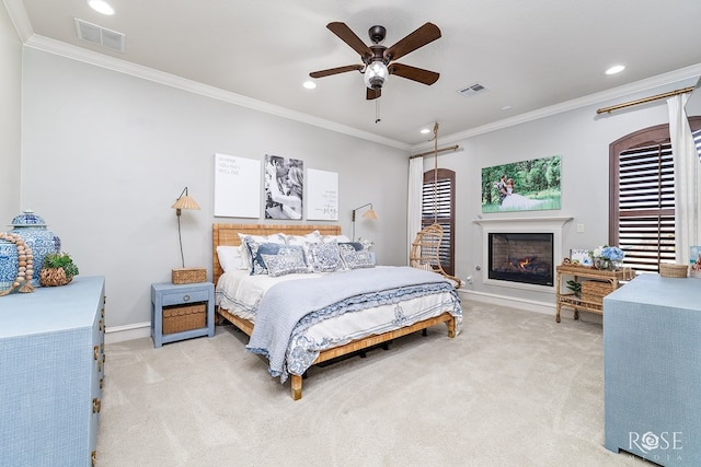 bedroom featuring crown molding, a lit fireplace, visible vents, and light colored carpet