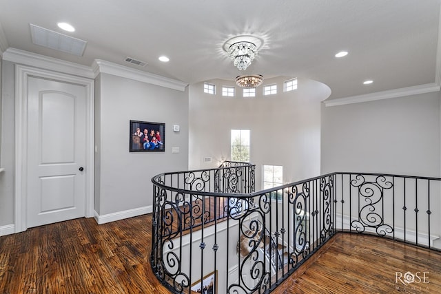 hall featuring visible vents, dark wood finished floors, ornamental molding, an upstairs landing, and a chandelier