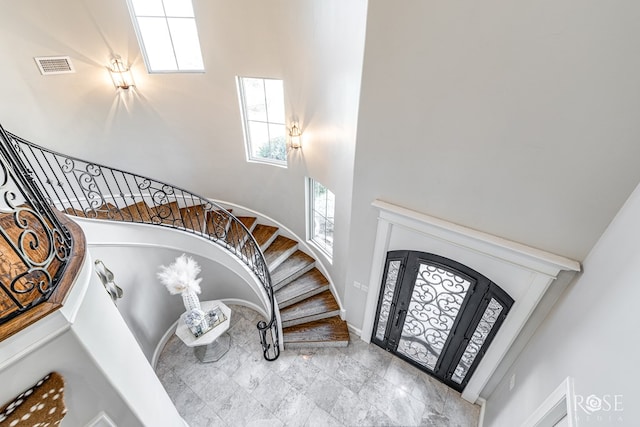 foyer entrance with baseboards, visible vents, a high ceiling, and stairs