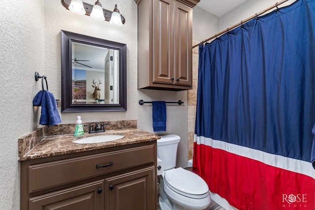 bathroom featuring a textured wall, vanity, and toilet