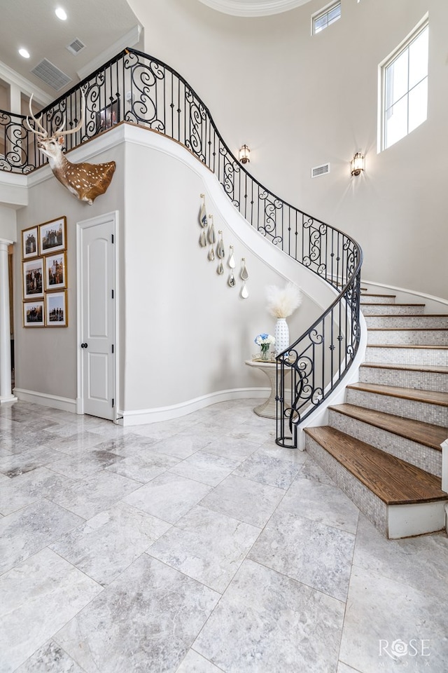 stairway featuring baseboards, visible vents, and ornate columns