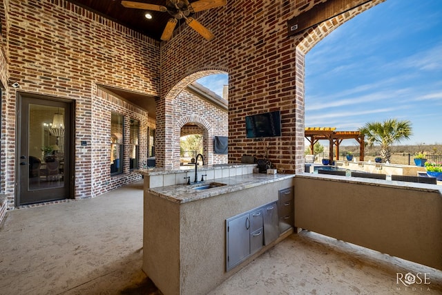 view of patio featuring ceiling fan, an outdoor kitchen, a sink, and a pergola