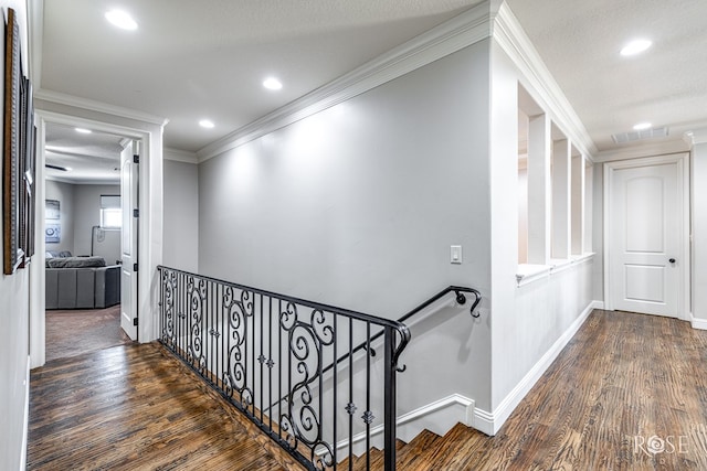 hall with crown molding, visible vents, dark wood-type flooring, an upstairs landing, and baseboards