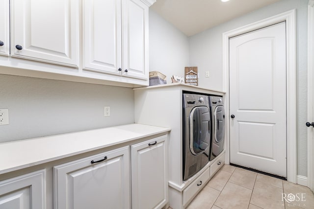 clothes washing area with light tile patterned floors, washer and clothes dryer, and cabinet space