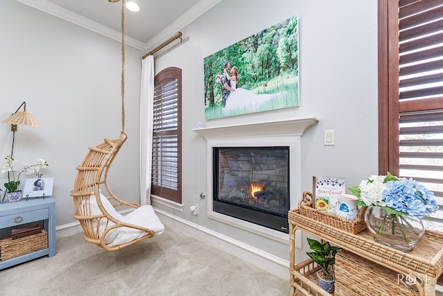 living area with baseboards, carpet flooring, crown molding, and a glass covered fireplace