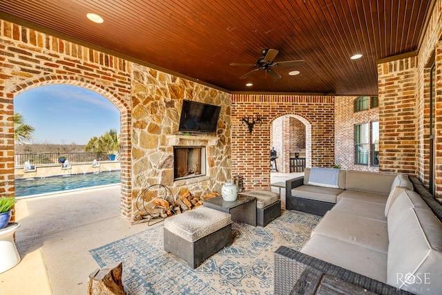 view of patio / terrace with an outdoor living space with a fireplace and a ceiling fan