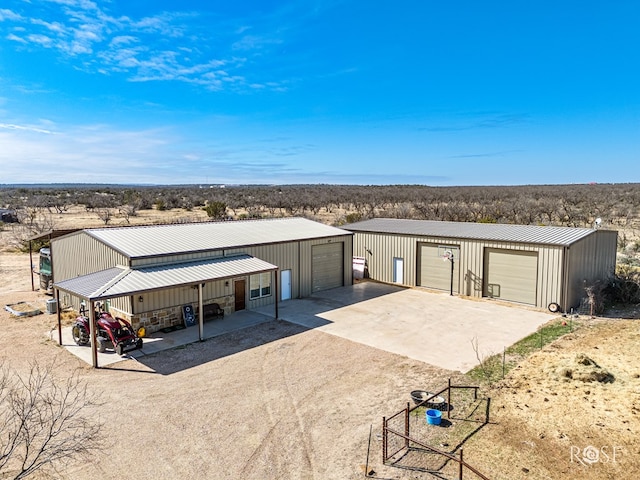 view of front of house featuring a garage, metal roof, driveway, and an outdoor structure