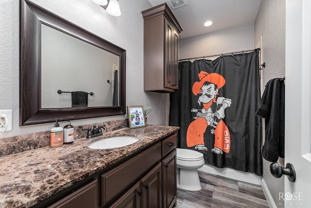 full bath featuring visible vents, a textured wall, a shower with shower curtain, toilet, and vanity