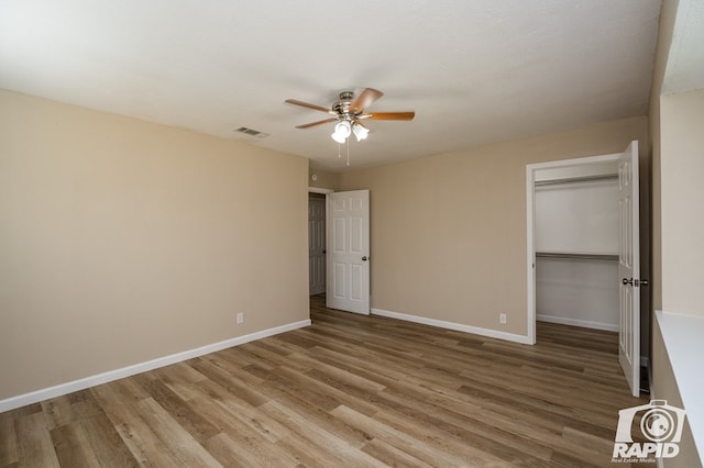 unfurnished bedroom featuring hardwood / wood-style flooring, ceiling fan, a spacious closet, and a closet