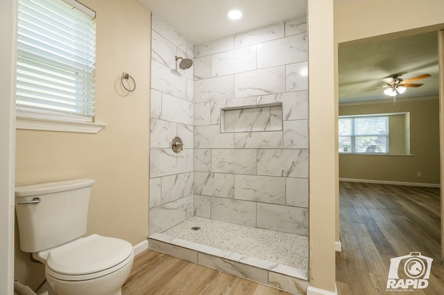 bathroom with hardwood / wood-style flooring, ceiling fan, toilet, and a tile shower