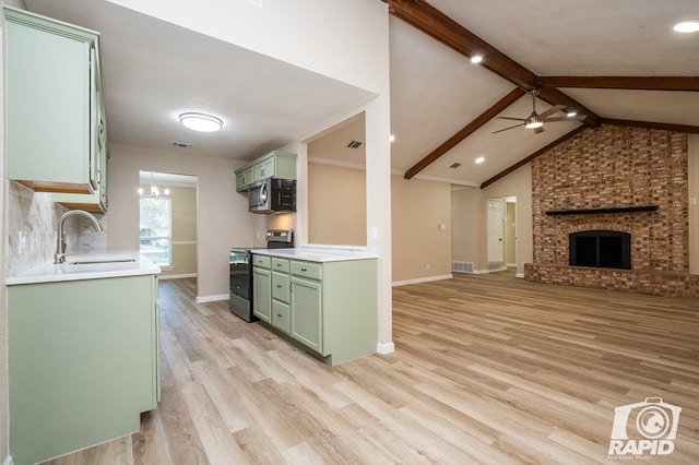 kitchen featuring sink, ceiling fan, stainless steel appliances, a fireplace, and light hardwood / wood-style floors