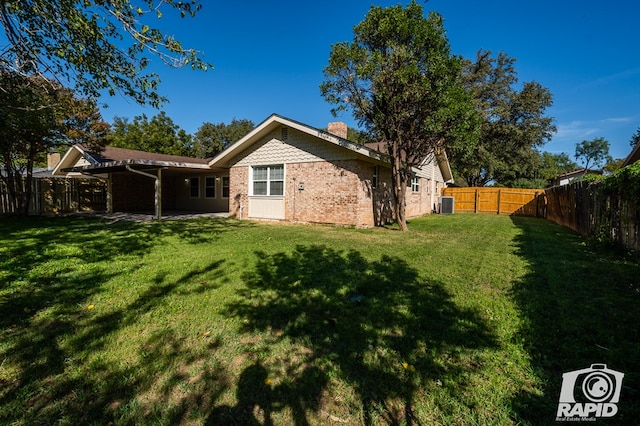 rear view of property featuring cooling unit and a lawn