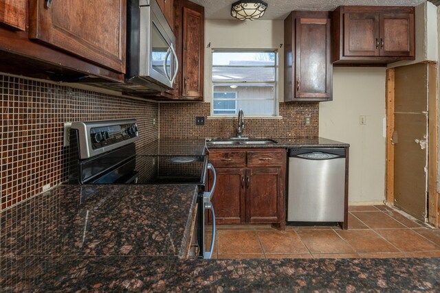 kitchen with appliances with stainless steel finishes, sink, decorative backsplash, dark brown cabinets, and a textured ceiling