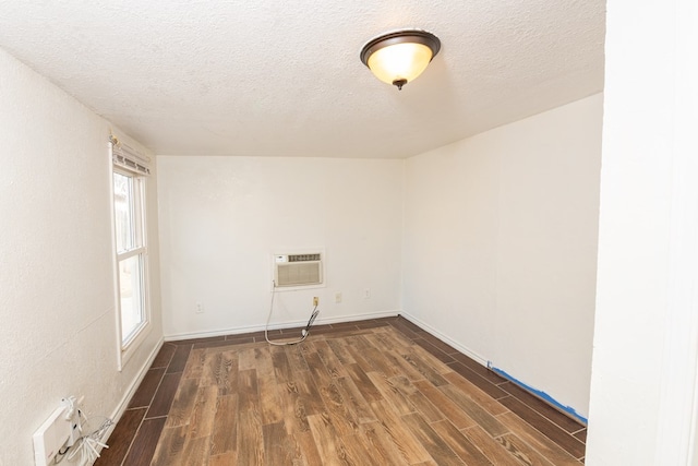 unfurnished room with dark wood-type flooring, a wall mounted air conditioner, and a textured ceiling