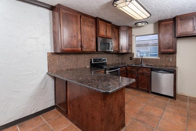 kitchen with sink, tasteful backsplash, dark stone countertops, kitchen peninsula, and stainless steel appliances